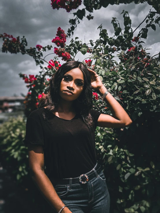 the young woman poses by some pink flowers