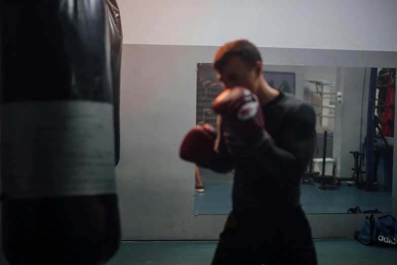 a man in a gym wearing red boxing gloves