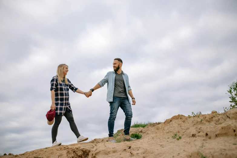 two people standing on top of a hill holding hands