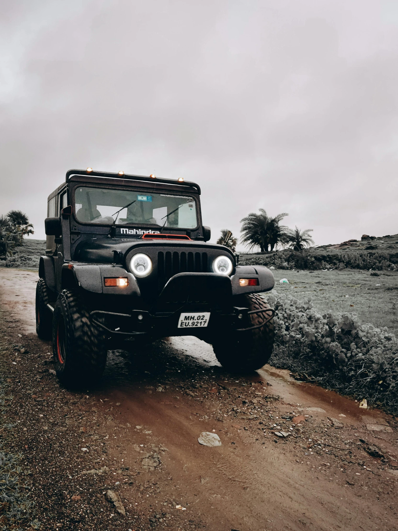 an old jeep sits in the middle of a dirt road