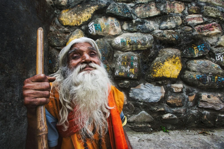 an old man wearing an orange outfit and holding a stick