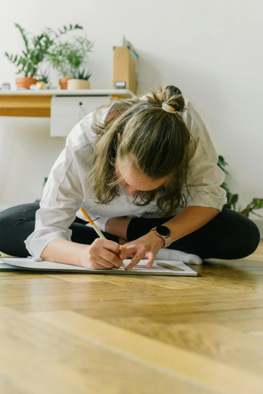 a woman writing on paper on the floor