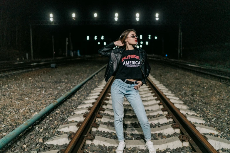 girl standing on a train track with her arm on her shoulder
