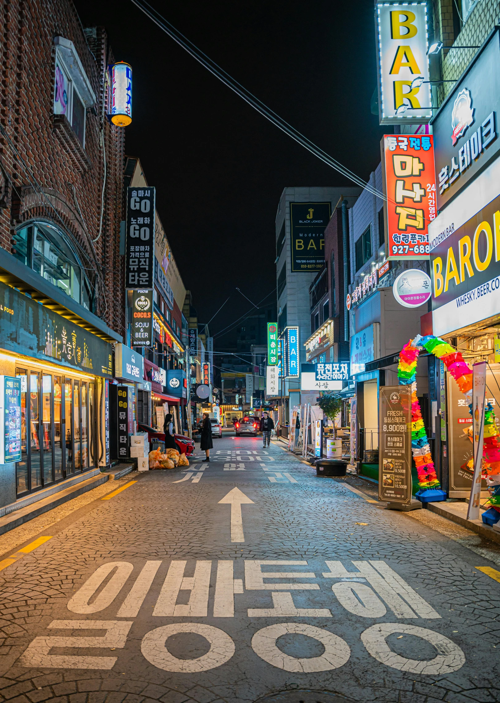 a shopping street at night, with colorful neon signs