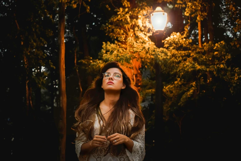 a woman in the middle of a wooded area with a light shiner above her head