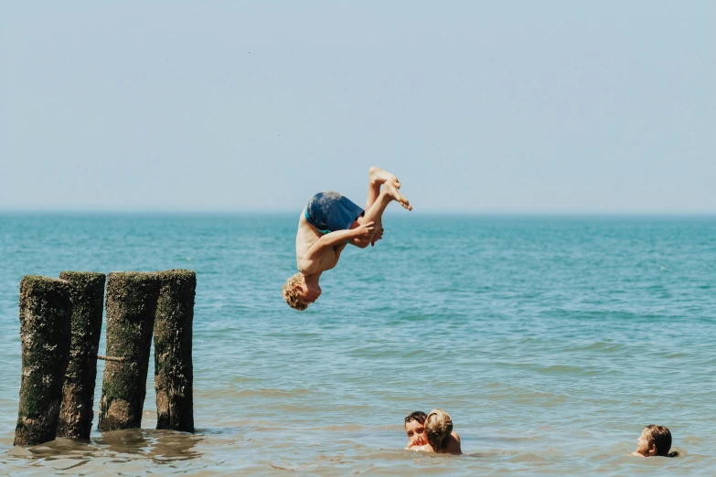 a man diving in to the ocean with his friends