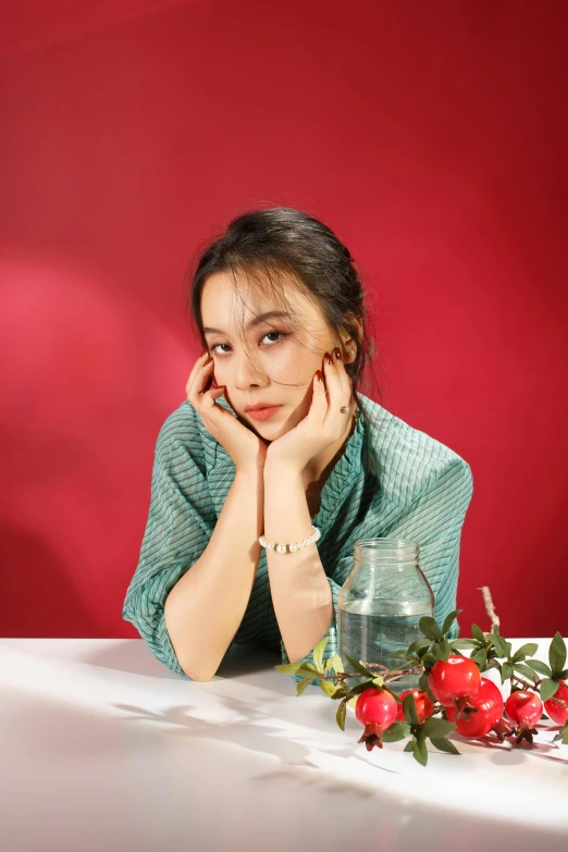 a girl sits at a table, leaning on her hand next to a vase