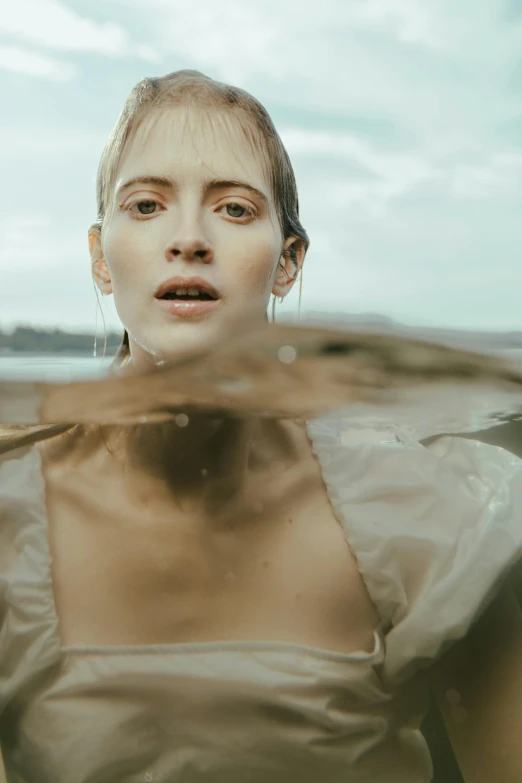 a woman looks at the camera while sitting in water