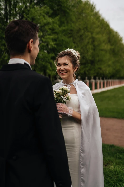 a newly married couple are talking together in a park