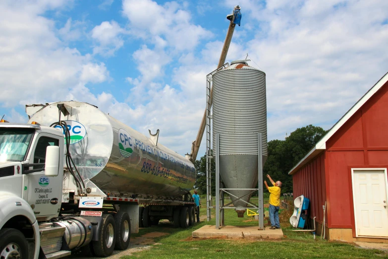 a tanker truck pulling another large tank off of a trailer