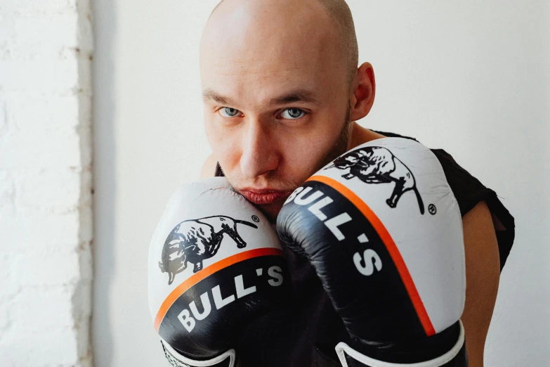 a bald man wearing a white shirt and boxing gloves