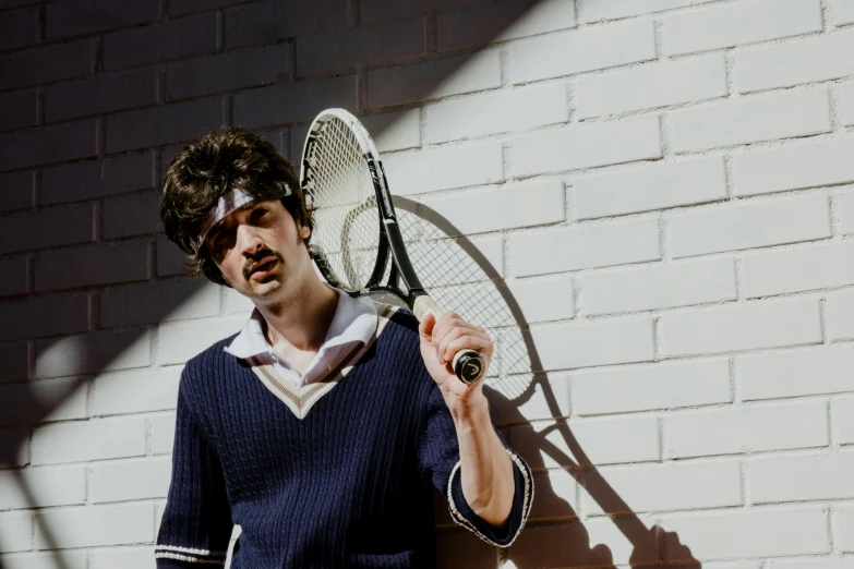 a young man holds his tennis racket up to the side