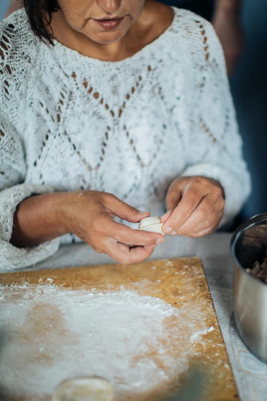 a person in white shirt kneading a food item