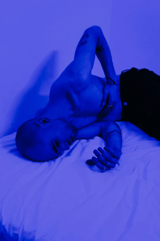 a young man laying on top of a white bed