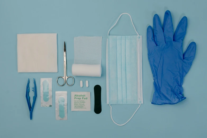 a pair of blue medical gloves, surgical gloves, sterile supplies and glasses are laid out on a blue background