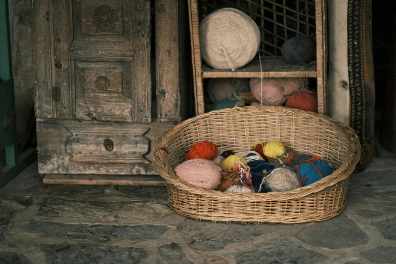 several yarns sit in a basket on a stone floor