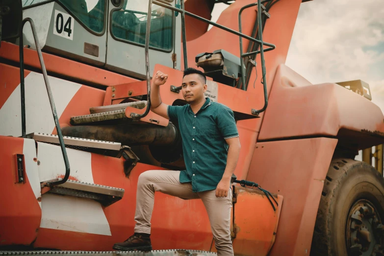 man posing in front of large tractor on cloudy day