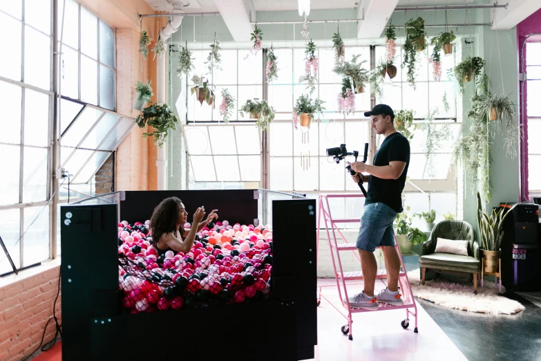 the video man is recording a girl standing on a luggage cart