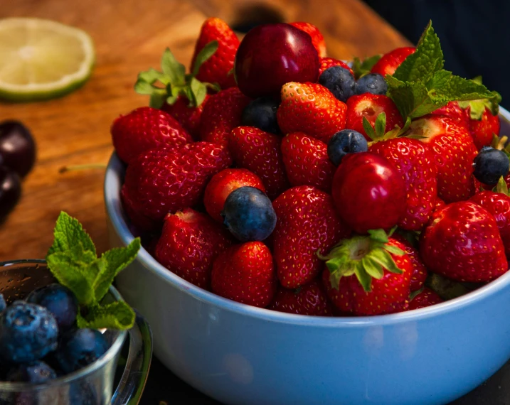 a bowl of strawberries, blueberries and kiwis