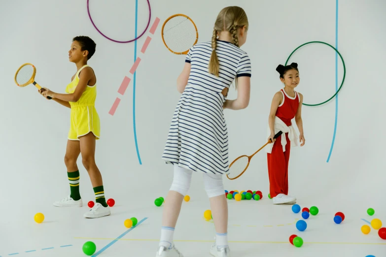 a group of three girls standing next to each other holding tennis racquets