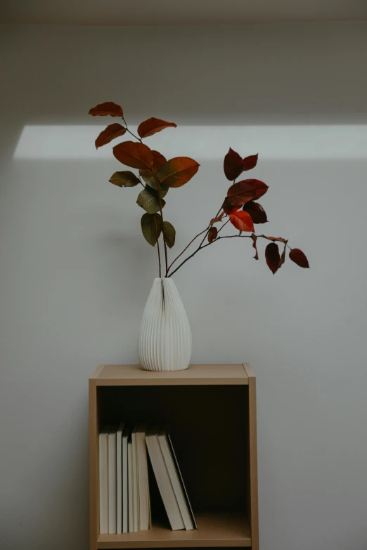 the vase is full of a few tiny leaves and one is standing on a shelf