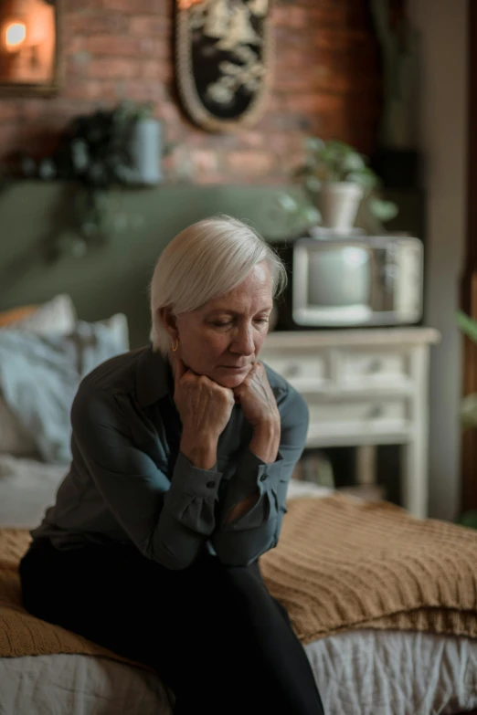 a woman sitting on a bed with her chin up