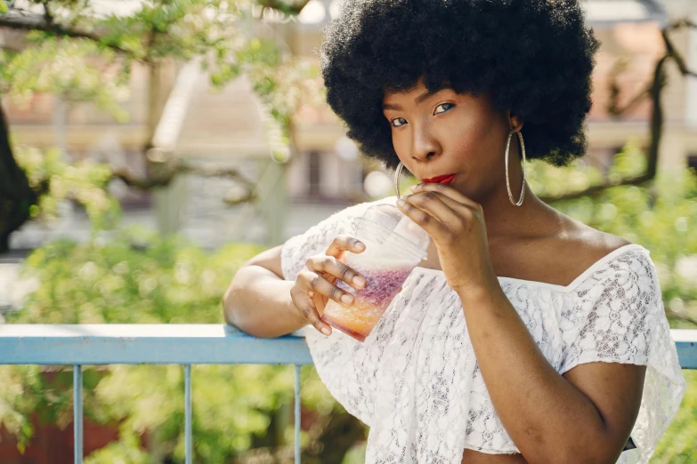 an african woman in a white dress is taking her cupcake