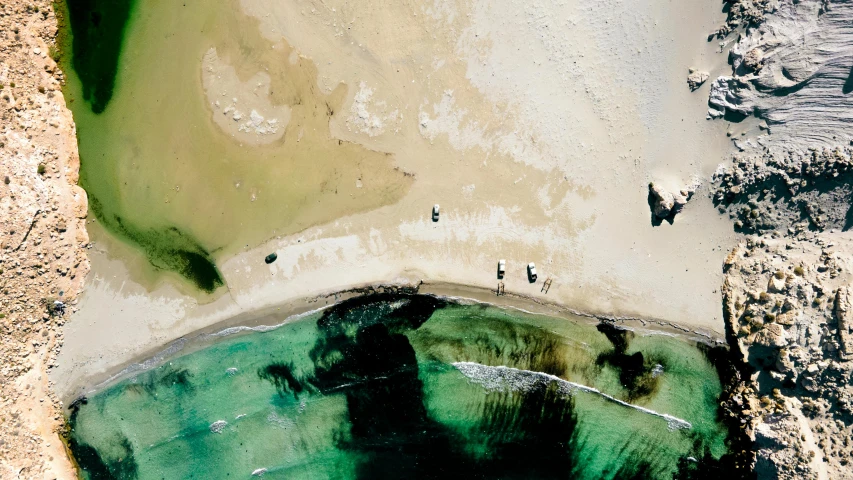 people walk along the shoreline near an expanse of water