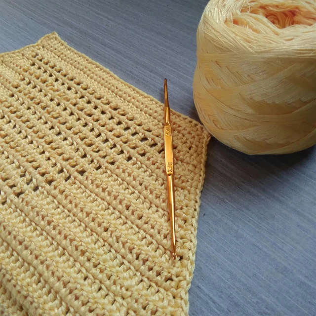 close up image of crochet and the thread, used to make a rug