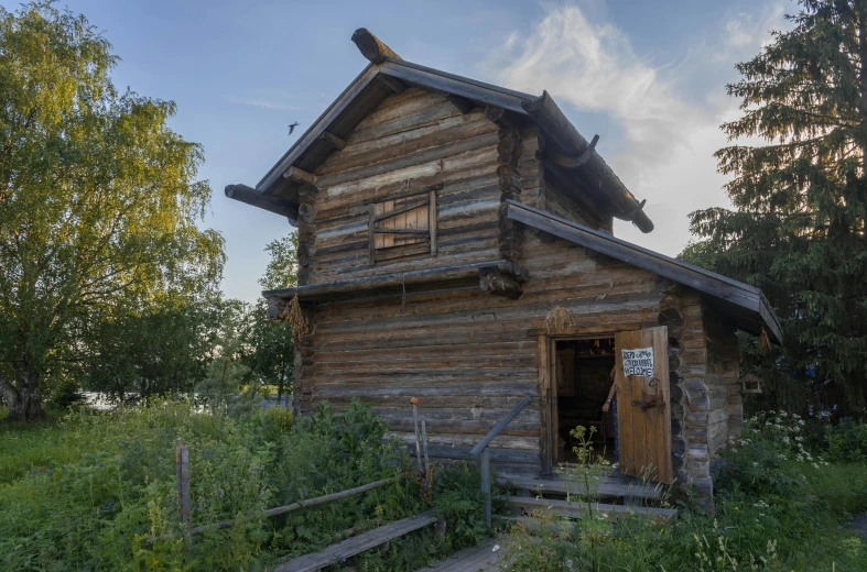 an old log cabin sits on a hill with trees in the background