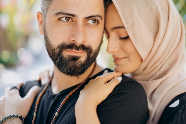 a young man is holding a woman who has a beard