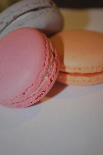 pink and yellow macaroons with white icing, on a plate