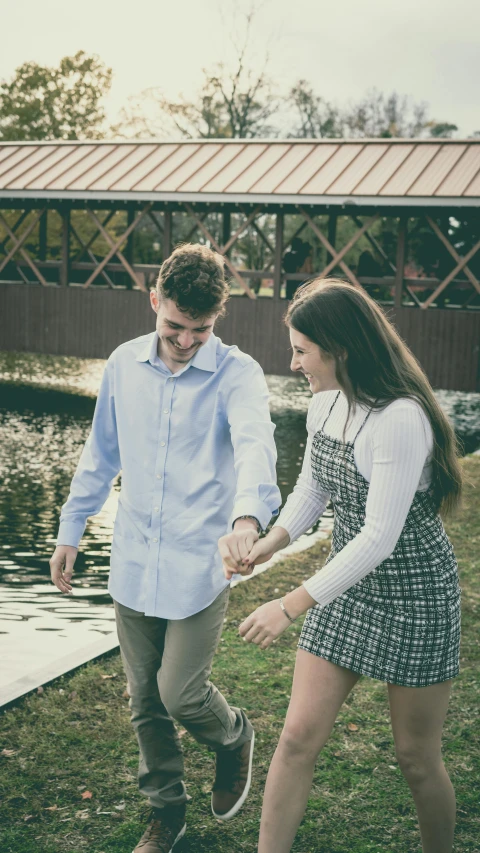 a man and woman playing on the grass by water