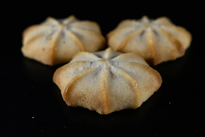 four tiny pastry pastries on a black surface