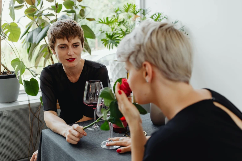 a man and a woman are sitting at a table with a wine glass