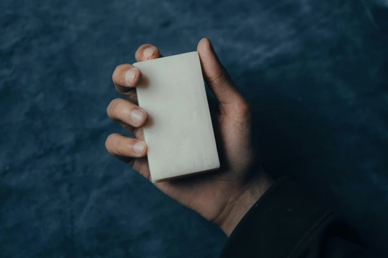 a hand holding a small rectangular block of paper