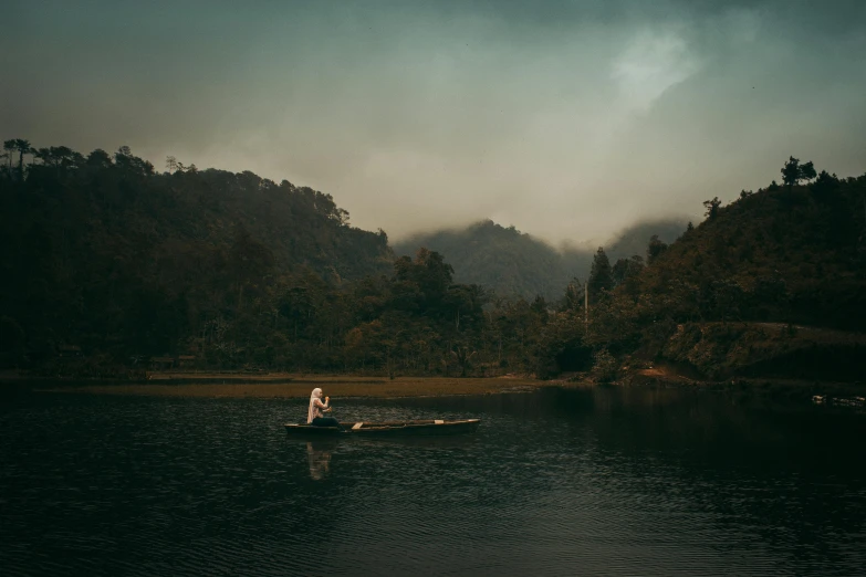 two people in a canoe in a lake near the woods