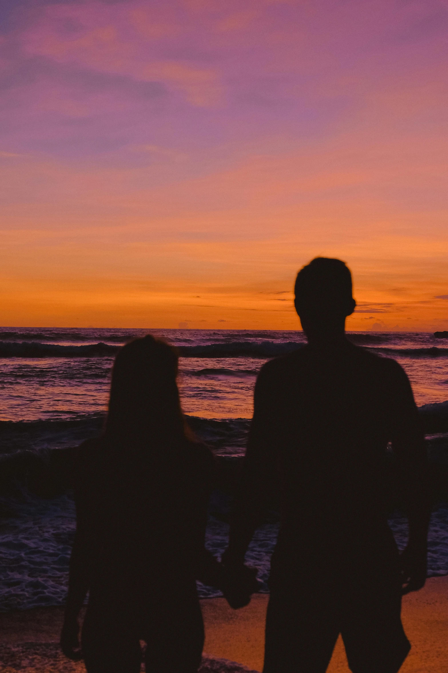 the couple is walking toward the water holding hands