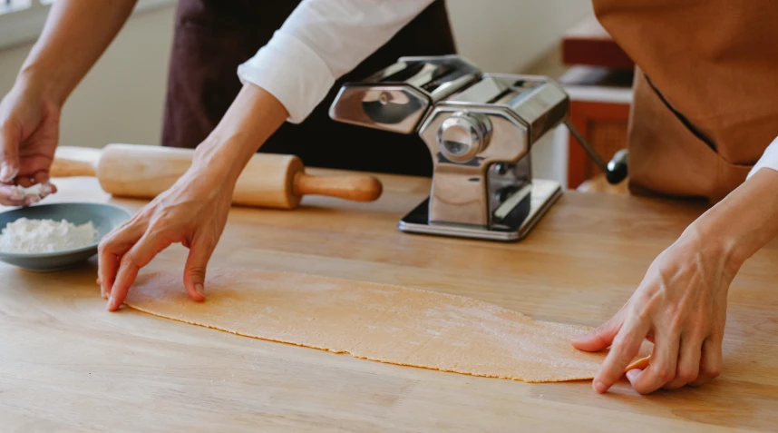 a group of people making some food on top of a wooden table