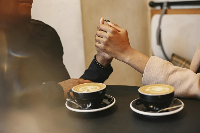 the two people are sitting at the table holding cups of coffee