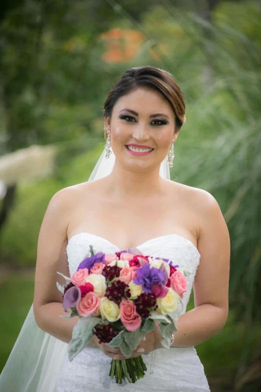 a bride holds her bouquet in the park