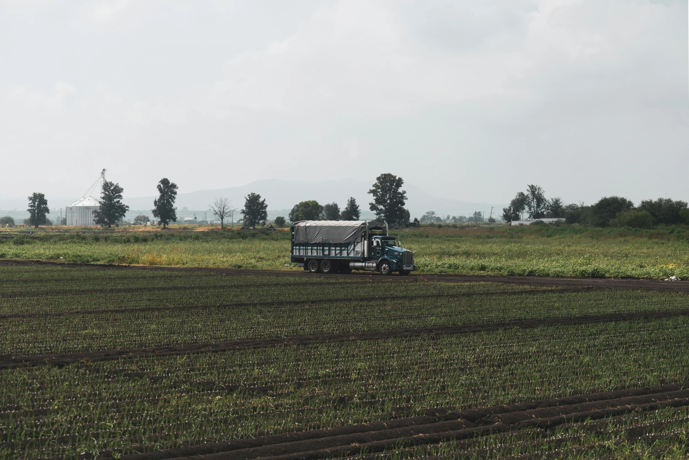 a tractor being plowed the field with two people nearby