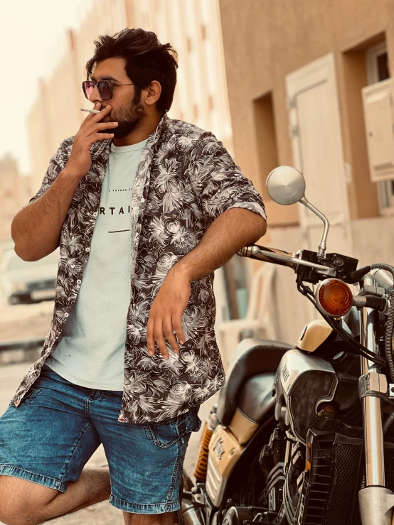 a person wearing a flower shirt is standing near a parked motorcycle