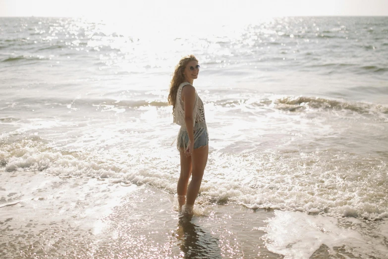 the young woman is standing in the surf on the beach