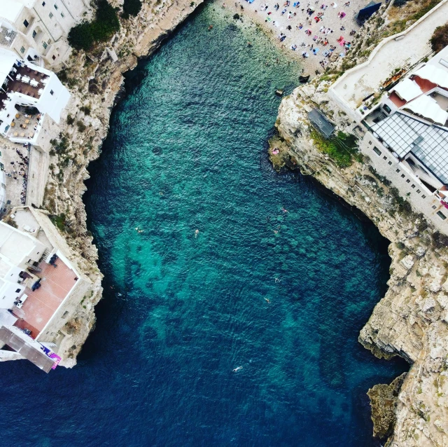 the blue waters are full of people, buildings and cliffs