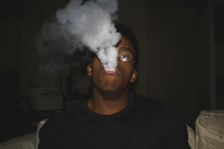 a man blowing out white smoke on his face
