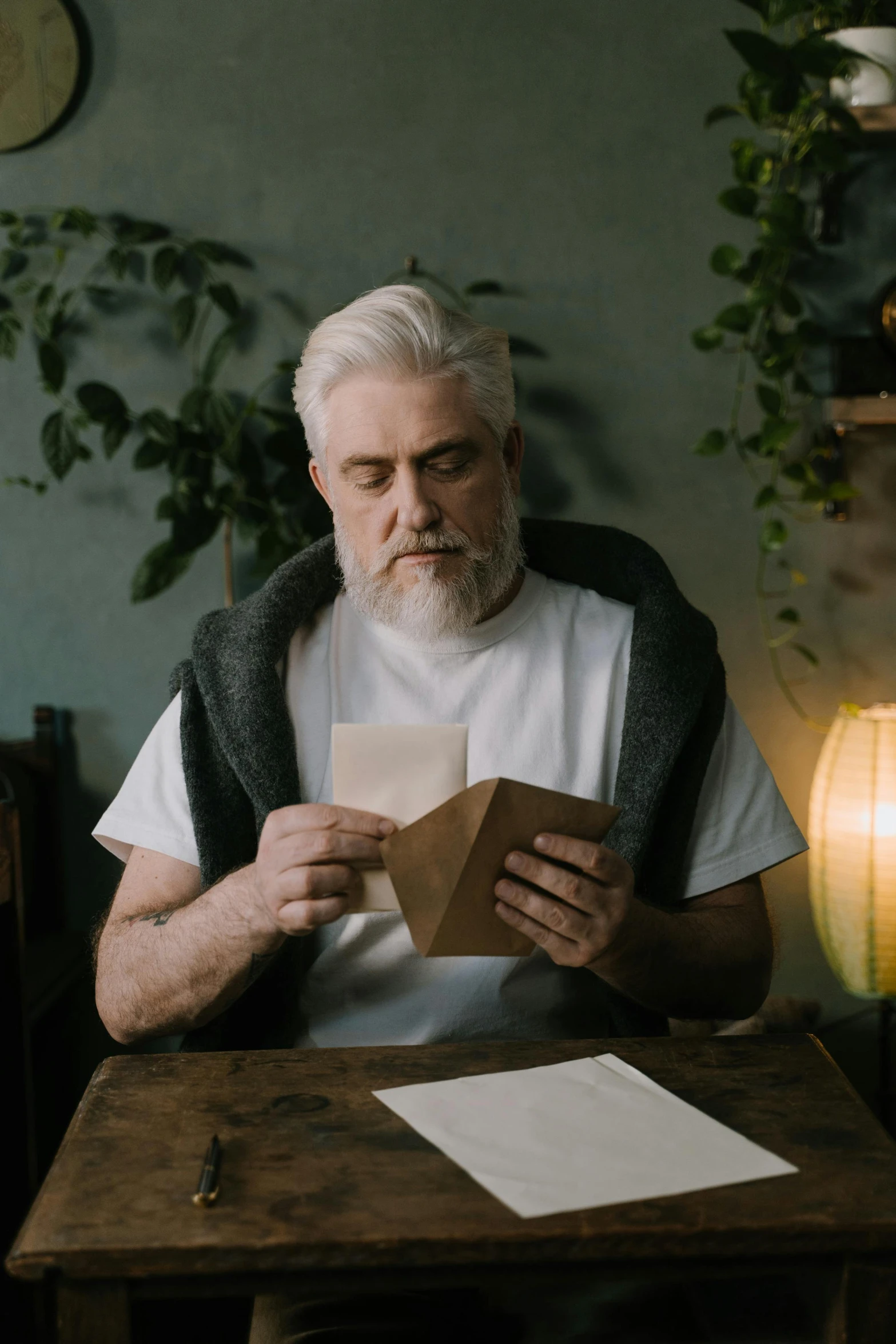 a bearded man reading a piece of paper on a table