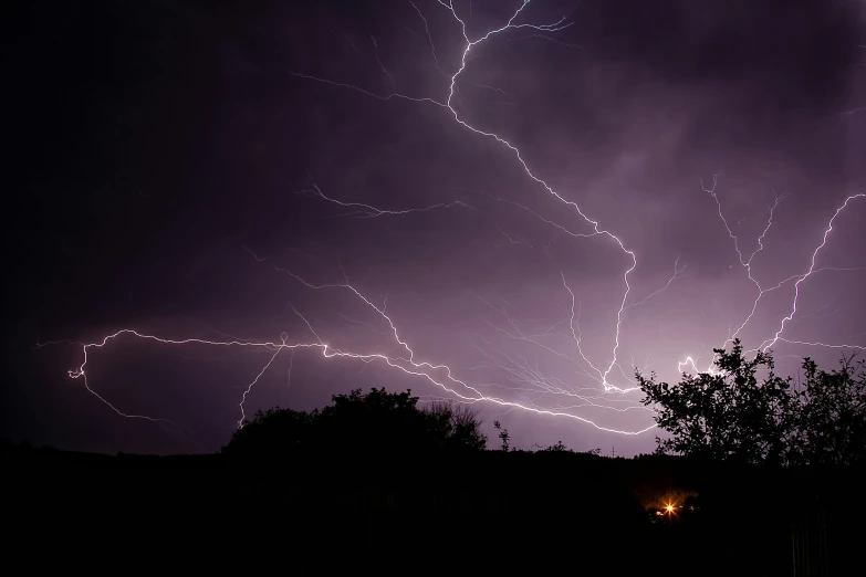 lightning striking through the sky over trees