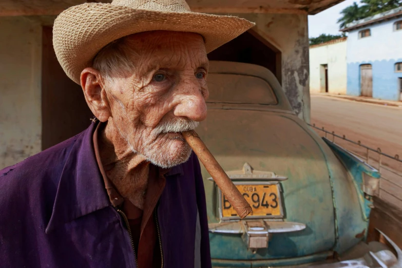 an old man wearing a straw hat smoking a pipe
