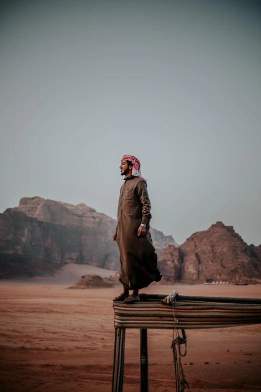 man in an desert setting stands on a rail